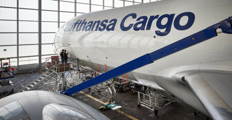 A Lufthansa Cargo 777 aircraft, with AeroSHARK film, is parked in the hanger.