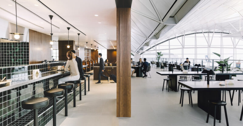 Cathay Pacific's The Deck lounge at Hong Kong International Airport. Floor to ceiling windows brighten a sleek open space with various seating.