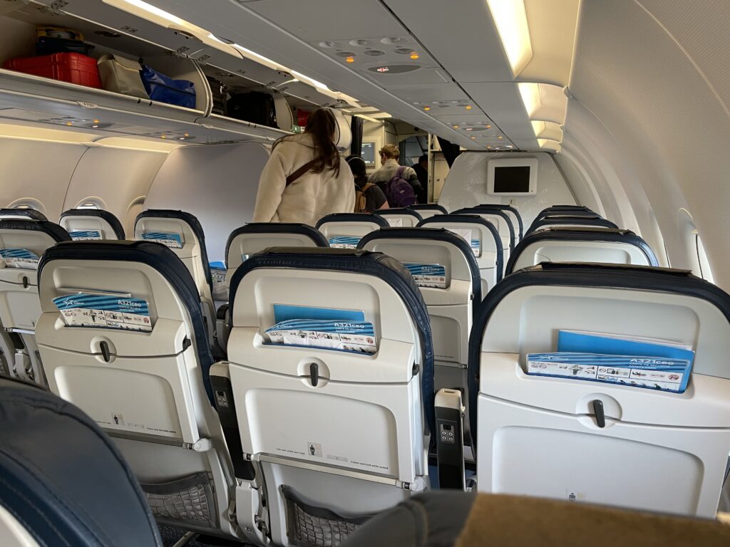 Inside the cabin of the Air Transat A321ceo. Bags are seen in the overhead bins as passengers file into the plane.