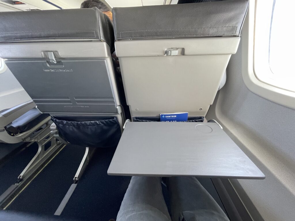 The large tray table is pulled out from the seat in front of the passenger.