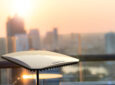 Electronically Scanned Array (ESA) technology by Intellian is being displayed in front of a city scape at sunset.