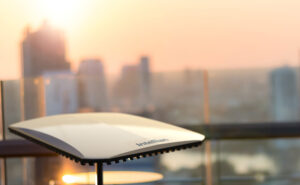 Electronically Scanned Array (ESA) technology by Intellian is being displayed in front of a city scape at sunset.