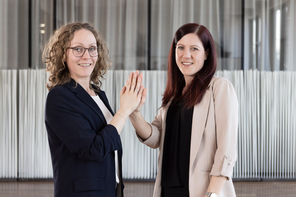 Kathrin Gerauer and Katharina Brunneder have been the first IT experts to implement the job-sharing concept successfully since last November. They are seen here with their hands touching.