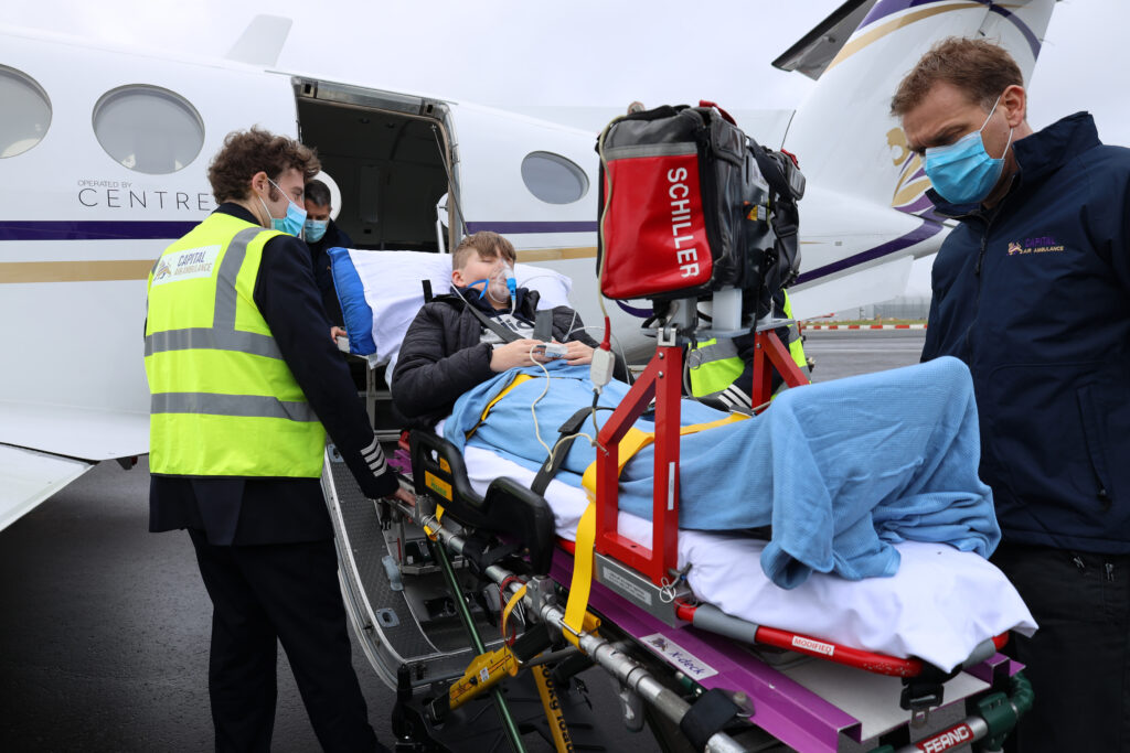 Capital Air Ambulance medics are talking to a young patient on a gurney as they prep to enter the aircraft.