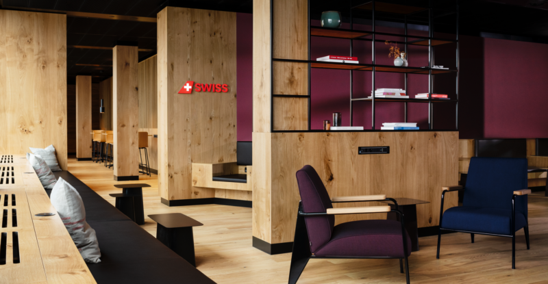 SWISS Non-Schengen Lounge at Zurich Airport is filled with various seating, wood finishes and maroon accents walls.