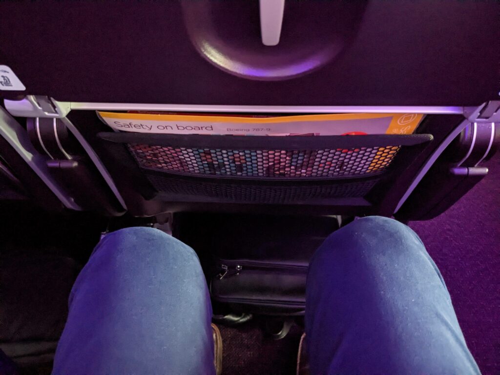 A man's knees are seen fairly close to the seatback in front of him on the Virgin Atlantic 787-9.