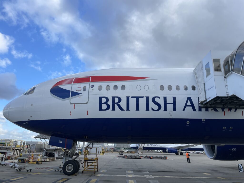 British Airways 777 is parked at the airport gate for boarding.