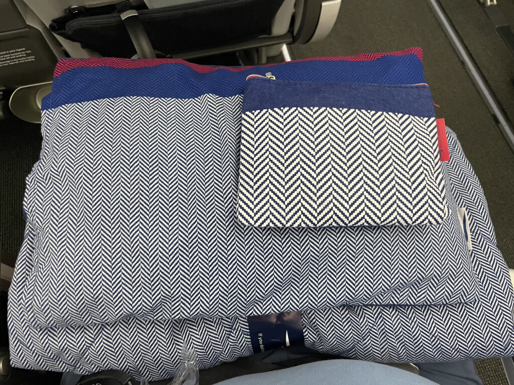 Grey and white zig-zag stripped bedding is laid out for the passenger on a British Airways flight.