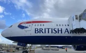 A jet bridge is attached to a British Airways 777 for boarding.