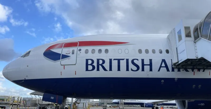 A jet bridge is attached to a British Airways 777 for boarding.