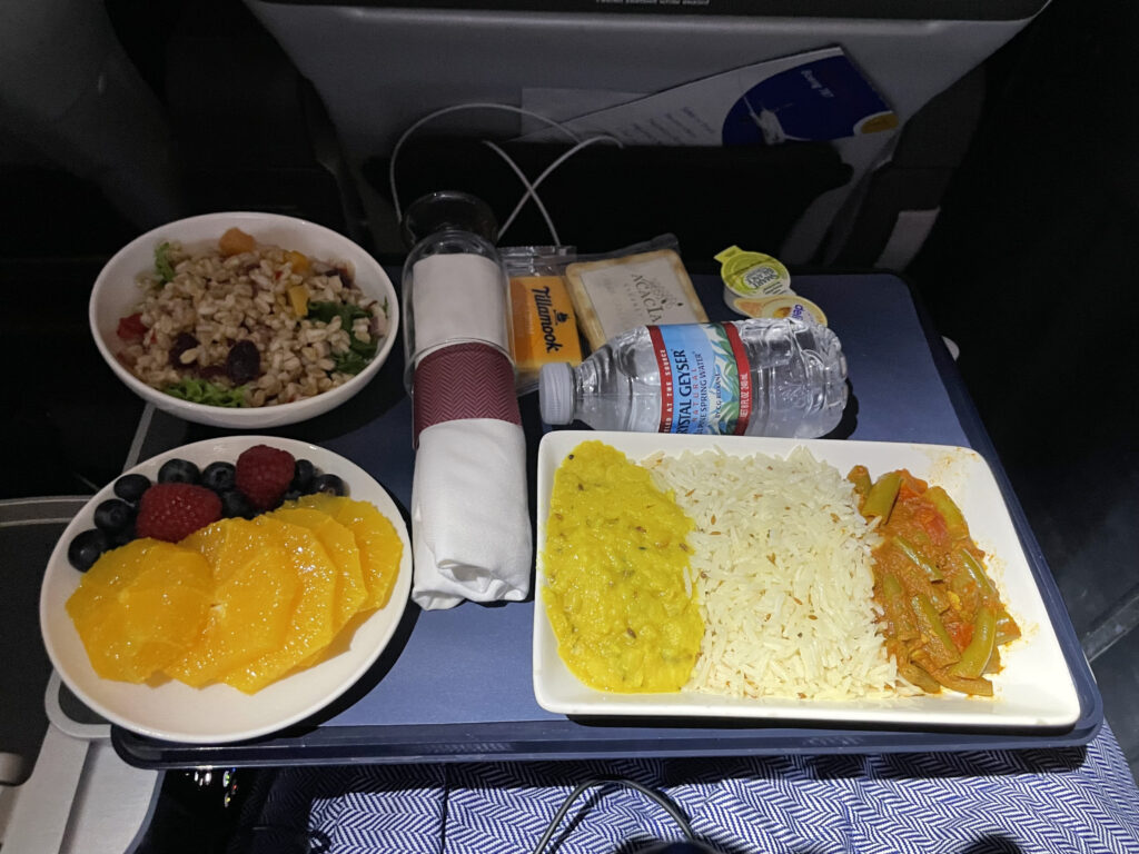 A beautiful meal is displayed on the aircraft tray table. 