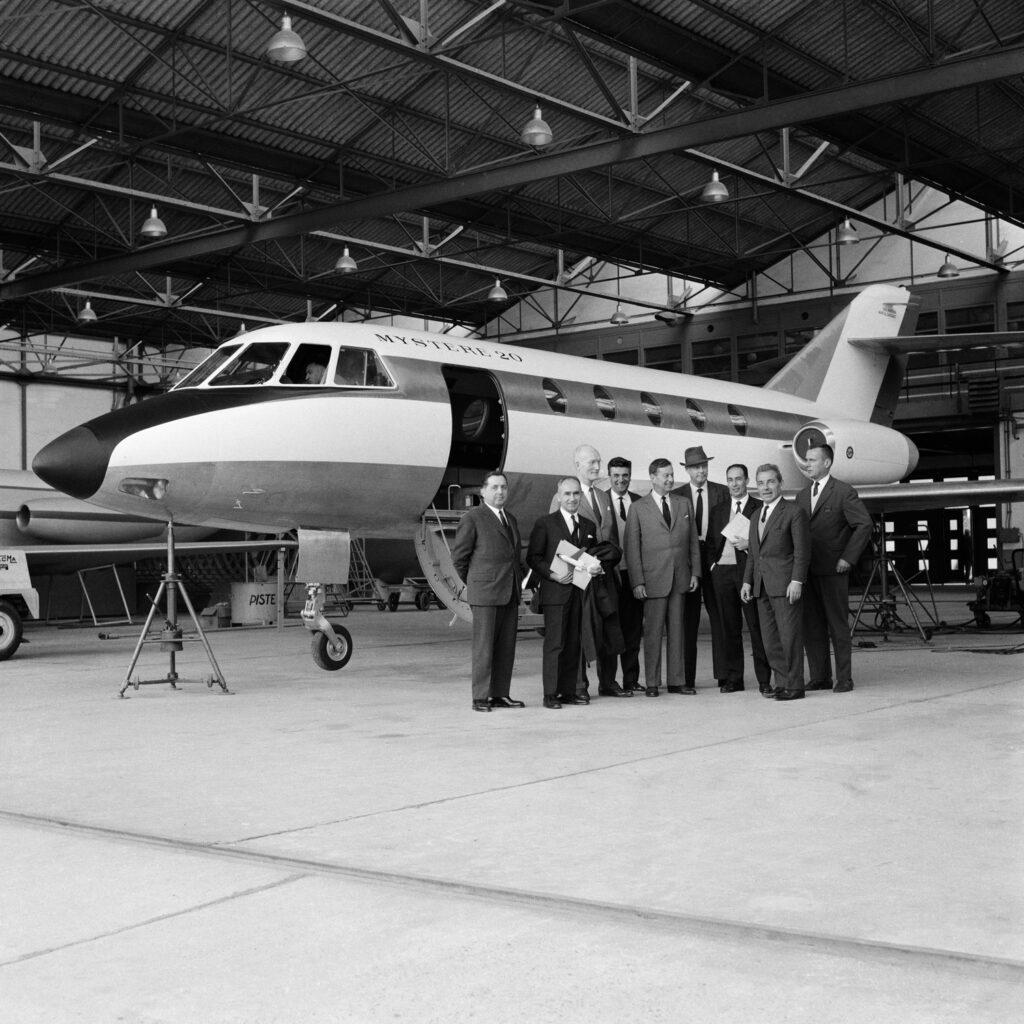 Charles Lindbergh drops by to inspect the new business jet on behalf of Pan Am. He is pictured here standing in front of the aircraft with a group of executives. 