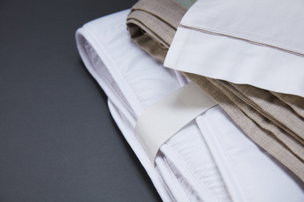 Three quality linens, two white one brown, are displayed on a black table.