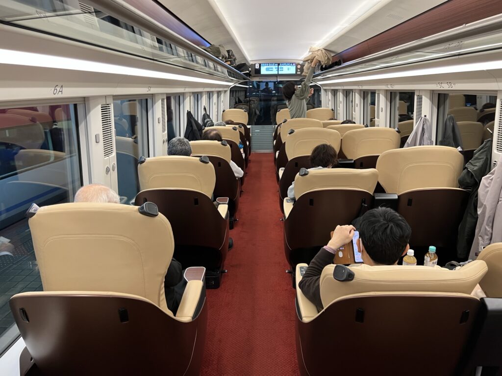 Hinotori Limited Express' premium cabin interior features red carpet and large cream colored seats. The layout is 1-2.