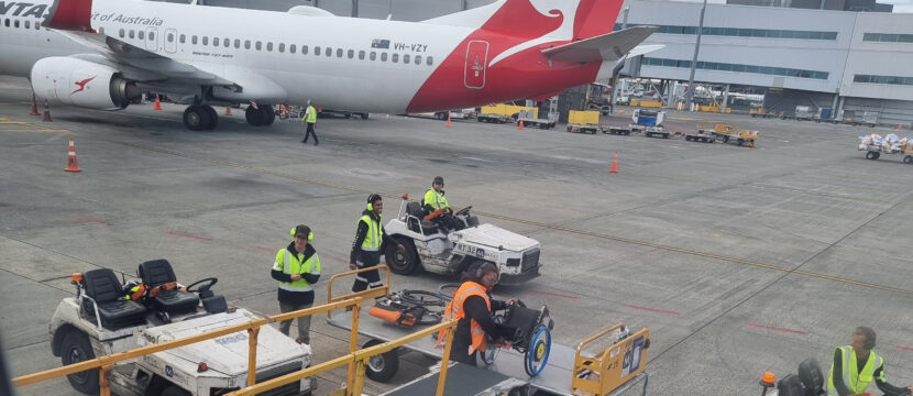 A wheelchair is removed from the belly of an aircraft.