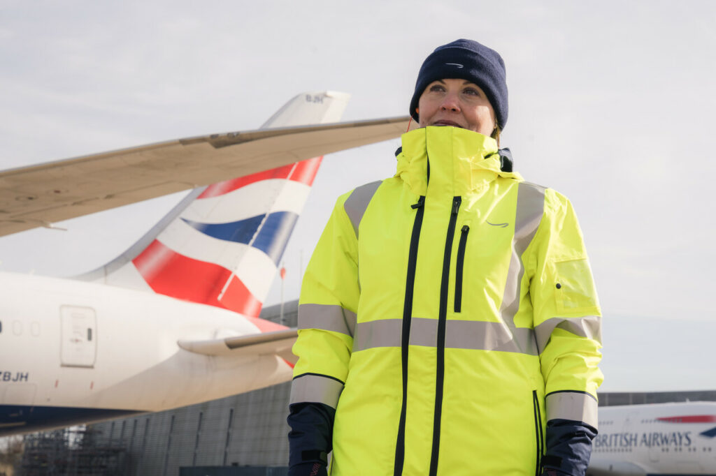 A woman is wearing a bright yellow coat as part of her operational ground teams uniform.