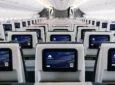 British Airways aircraft cabin from the back in economy class. Seatback IFE screens are in view, showing the Paramount+ channel