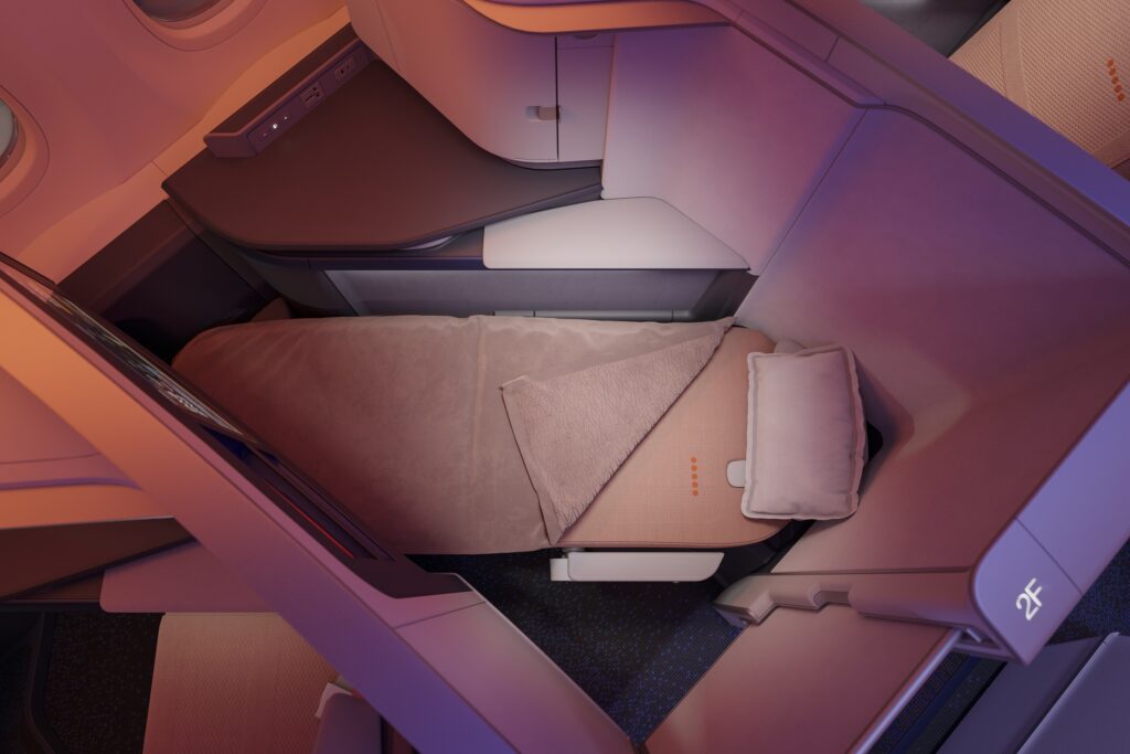 A view of the flydubai Safran Vue business class seat in its full-flat bed form, with a pillow and blanket laid out on the seat.