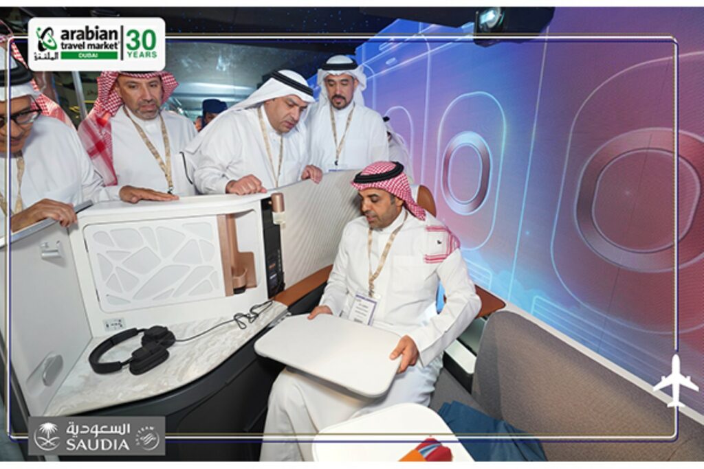 A group of men sit in and stand around the new Business Class seat on the Airbus A321 XLR. Image: SAUDI