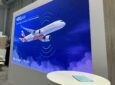 A large screen at the AIX 2023 Airbus press conference in Hamburg is showing an Emirates aircraft as part of HBCPlus.