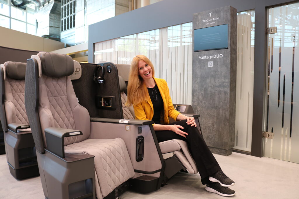 Mary Kirby demonstrating the Thompson VantageDUO business class seat at AIX 2023. Image Thompson Aerospace