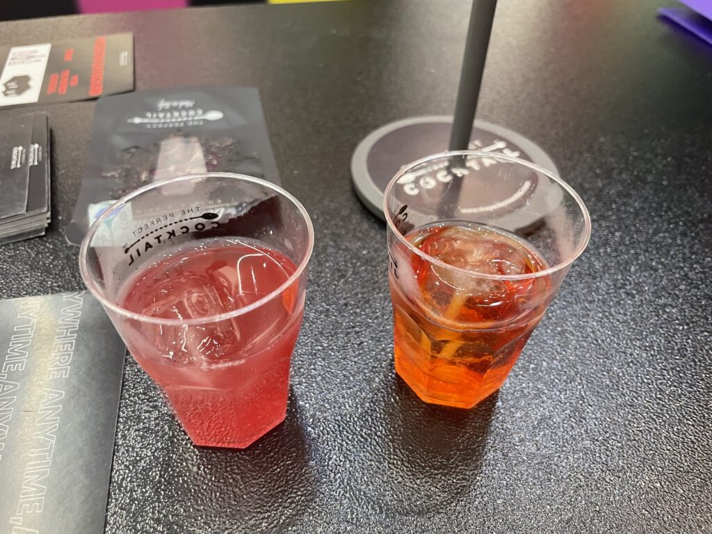 Two mocktails on a black table, one of them is the nonalcoholic negroni beverage.