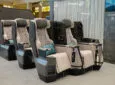 Four staggered Vantage Duo business class seats are being displayed at AIX 2023. The seats are an mixture of grey tones with a light blue pillow.