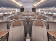 Head on view of Recaro business class seats in a widebody. The seats are greyish in tone with a light brown headrest and detailing.