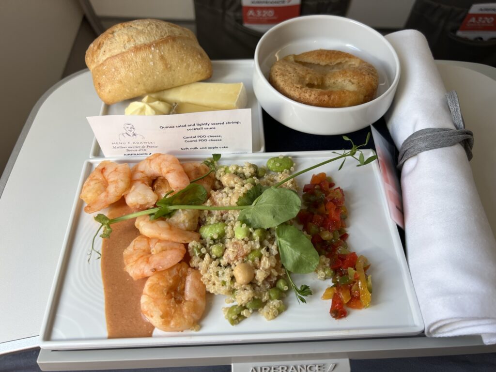 A meal of shrimp, quinoa, veggies and a roll are served on the Air France flight.