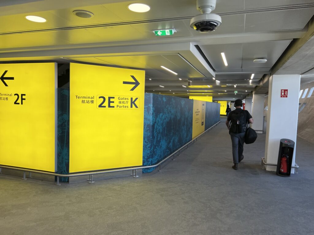 Signs, on a bright yellow board, showing the direction to go to access 2E or 2F