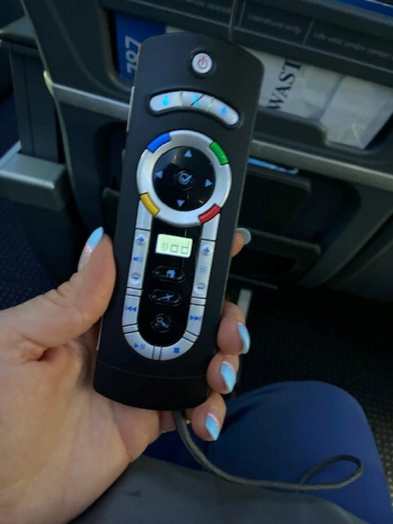 A passenger is holding up the embedded IFE remote for a closer look.