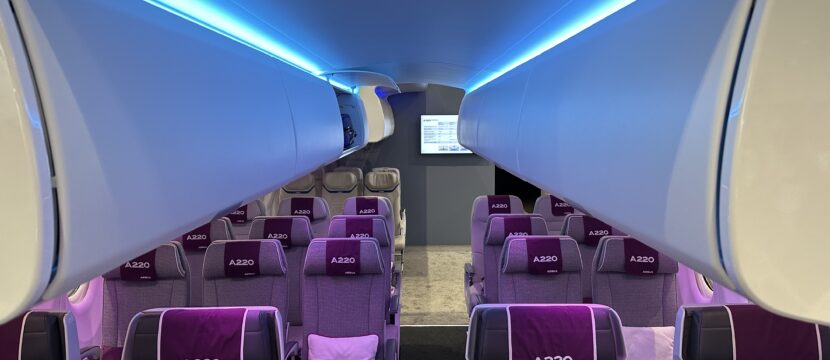 Airspace cabin display at the AIX 2023 show in Hamburg. Blue LED lights accent the large overhead bins while purple LED lights highlight the grey seats.