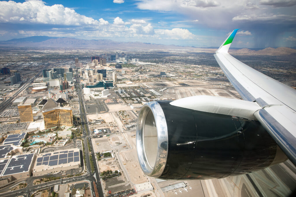 Looking out the window of the 757 over Las Vegas. The twinjet's engine is in view, with the cowling painted black. The wingtip is blue and green.