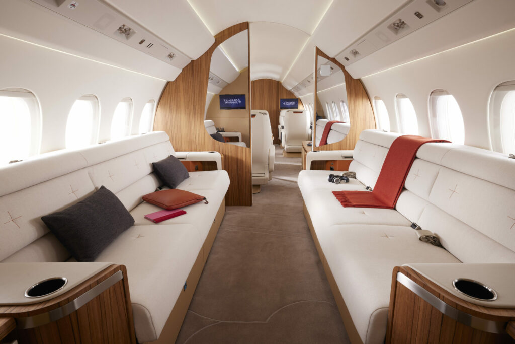 Dassault Aviation Falcon 6X cabin interior showing twwo long white couches with red blankets for seating.