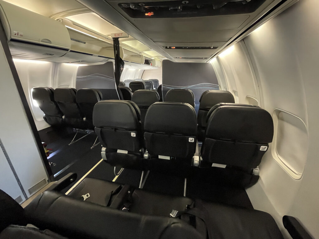 The aircraft is in a 3-3 layout with black seats that have minor white detailing. This view is of the back of the seats.