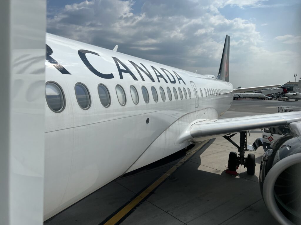 Looking out the airport window to see the side of the parked Air Canada A220