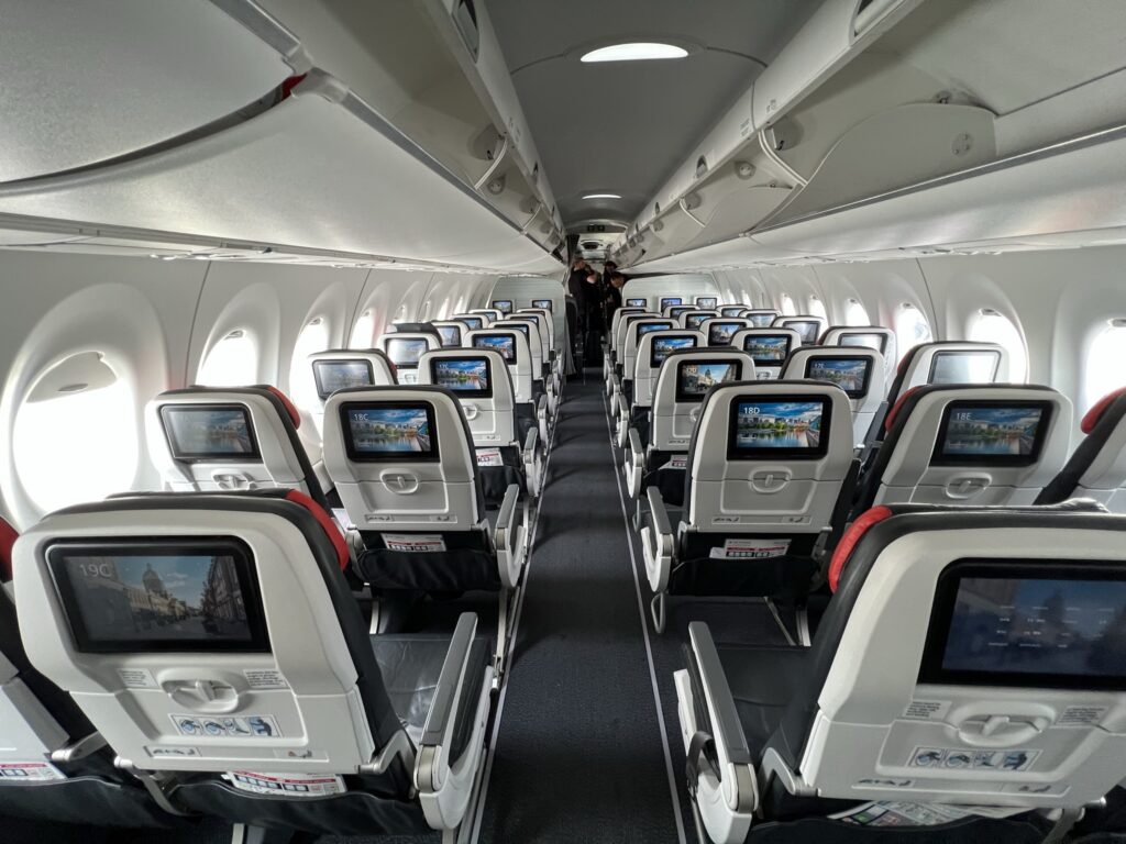 Air Canada A220 cabin in a 2-3 layout with large overhead bins, new seats and bright, modern seatback IFE.