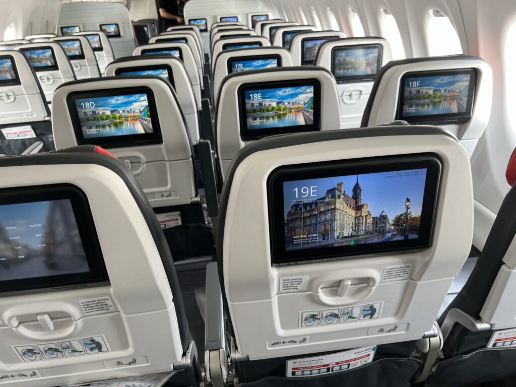 The welcome screen on the Air Canada A220 is a scenic photo of a historic building and the passenger seat number. 