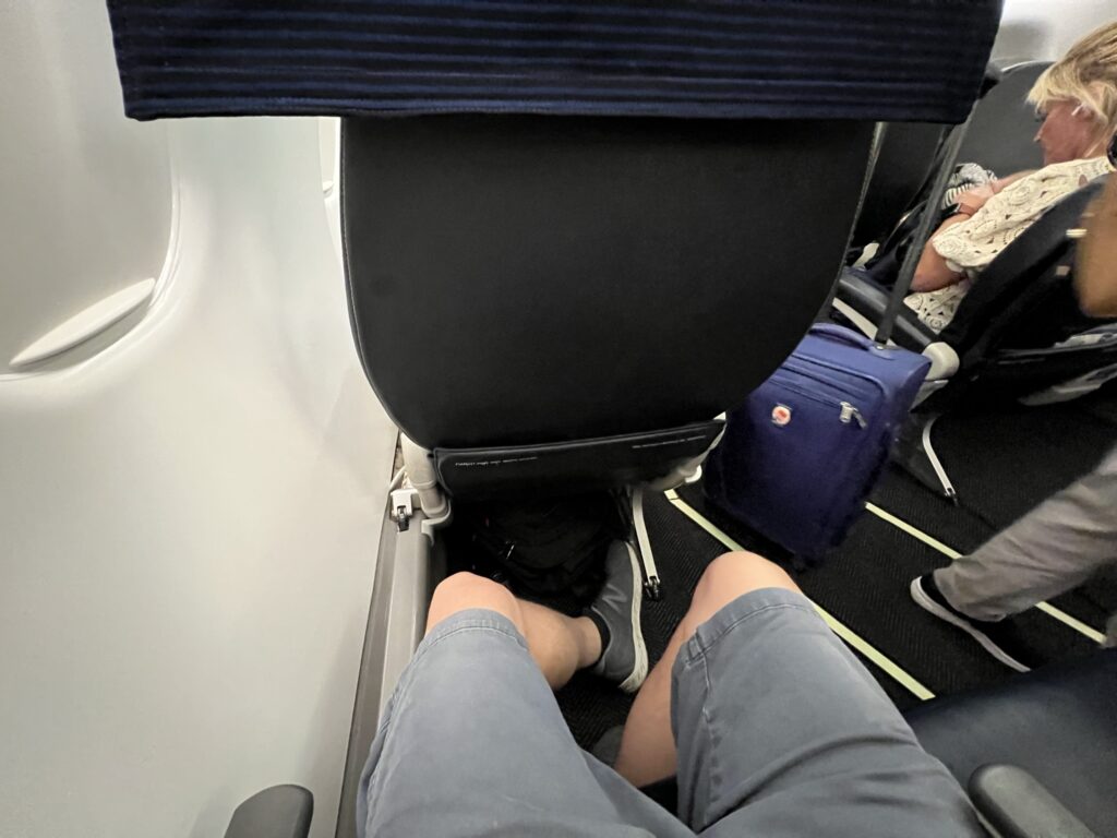 The author is seated on board the United ERJ175. His legs are shown and he has ample legroom.