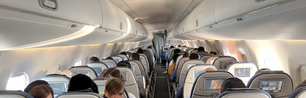 Inside an Air Canada E175 filled with passengers in 2-2 configuration. The overhead bins are small.