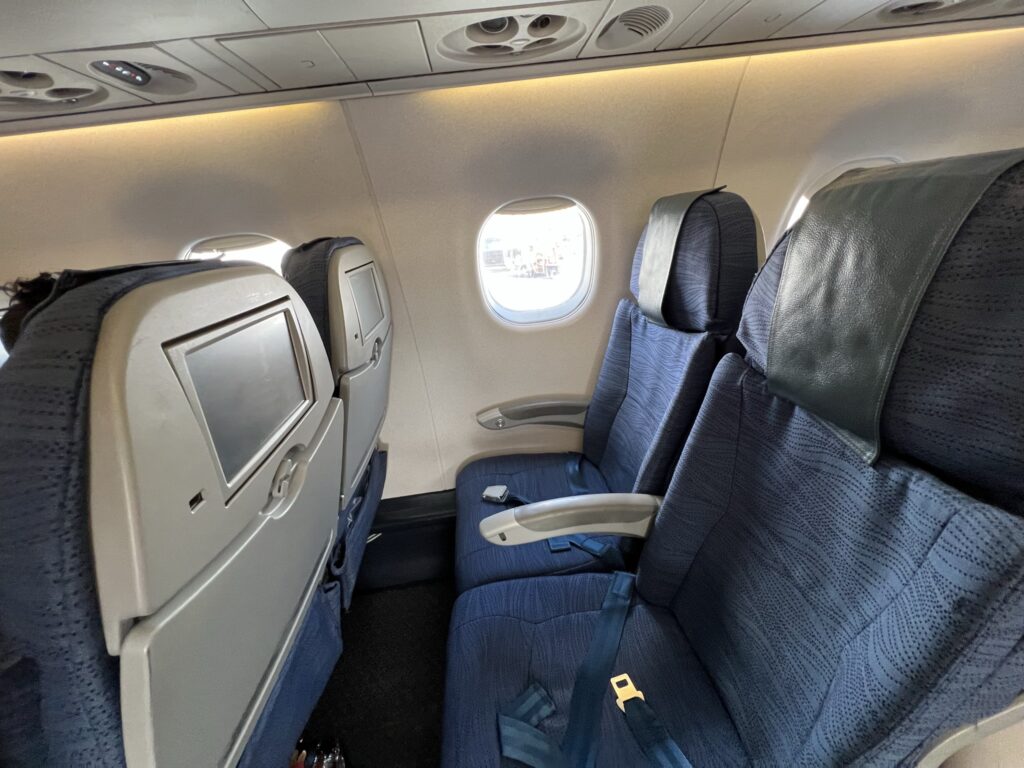 Air Canada E175 seats are blue in a 2-2 configuration. Two comfortable looking seats are shown in this photo.