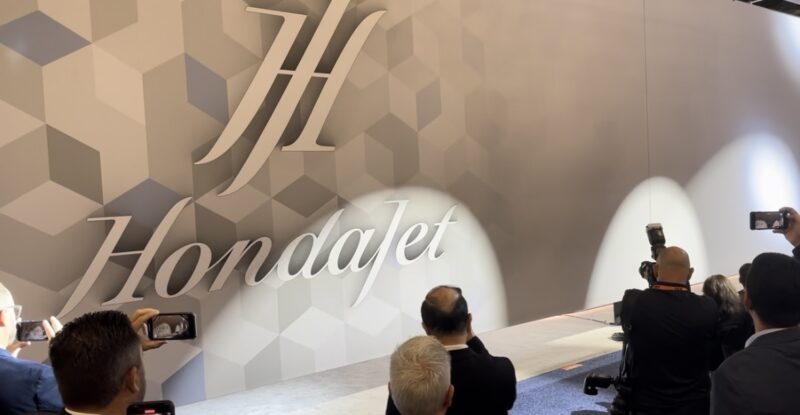 Hondajet logo is displayed on a large wall during a press reveal.