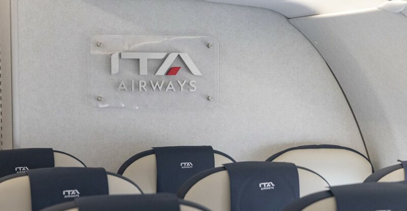 ITA Airways crest by ABC International is seen above three economy class seats.