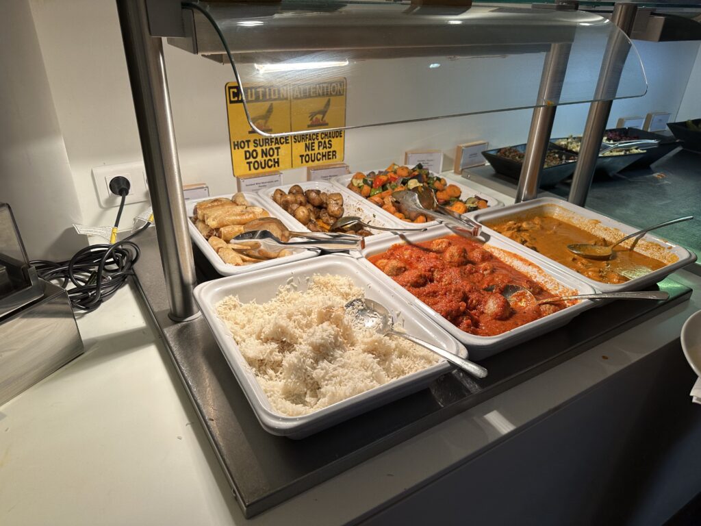 Various buffet items are seen here including potatoes, mixed veggies, rice, spring rolls, meat balls and a chicken curry