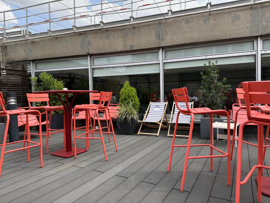 Tall chairs sit at high red tables in the outdoor patio section of the Star Alliance lounge.