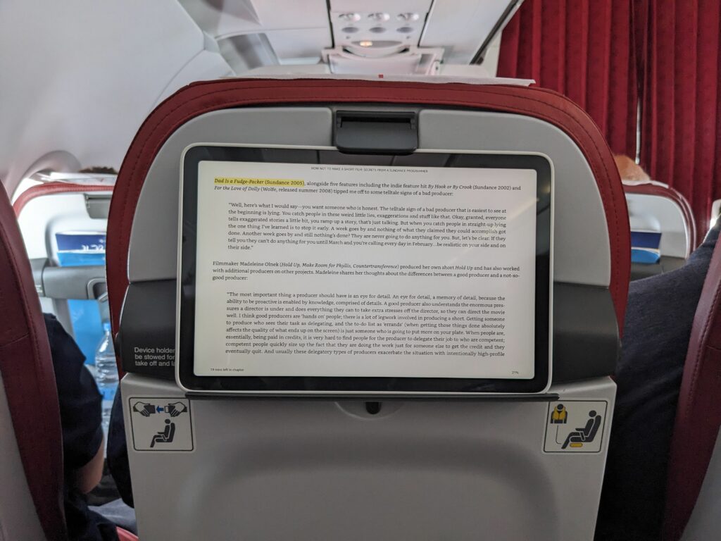 A tablet is sitting on the Air Malta seatback tablet holder. 