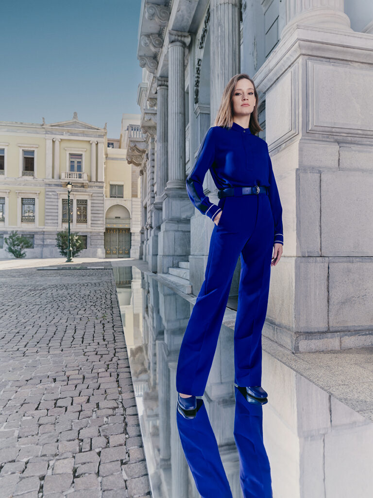 A woman is modeling the sleek blue Aegean crew pant suit uniform by Zeus+Δione