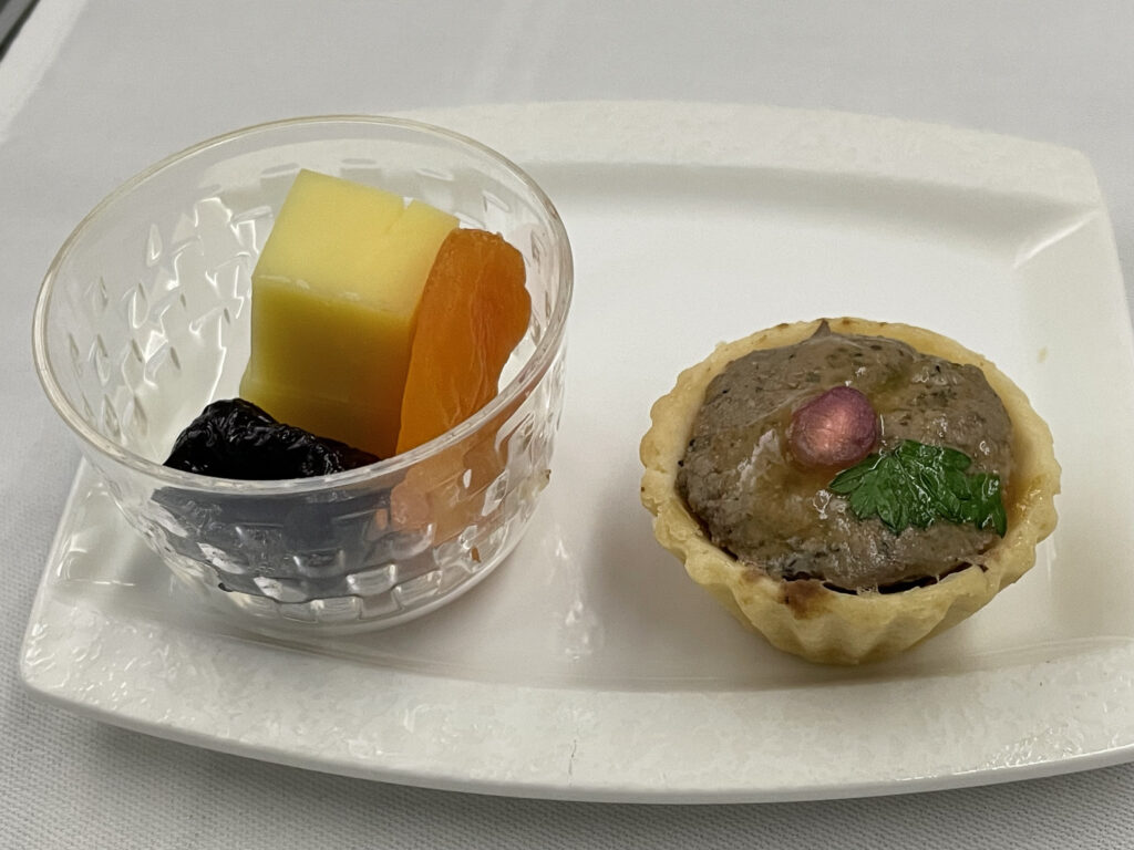 A plate that contains a tart and a small glass bowl of fruit