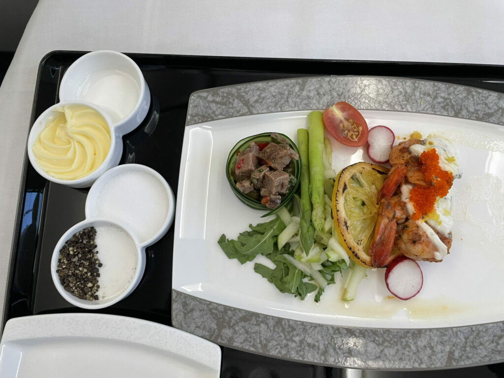 Various vegetables and salad are carefully laid out on white crockery, and sit atop the tray table.