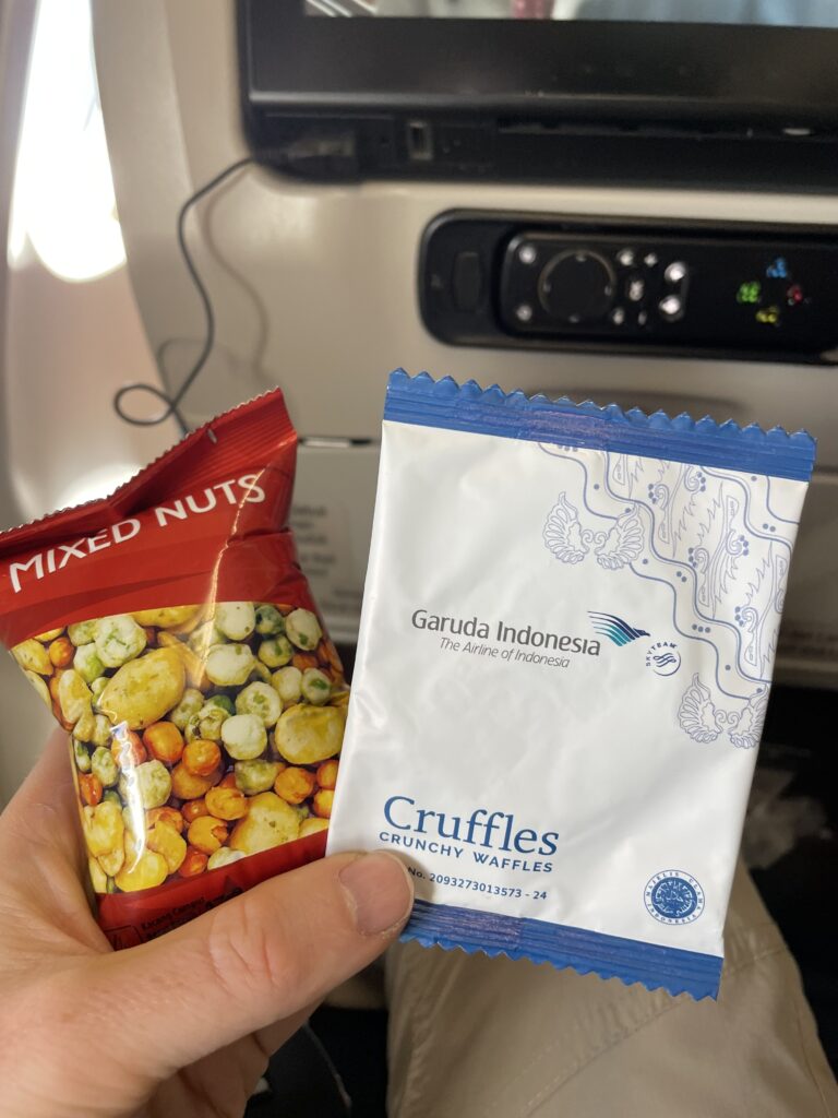 A passenger is holding up two snacks from Garuda Indonesia